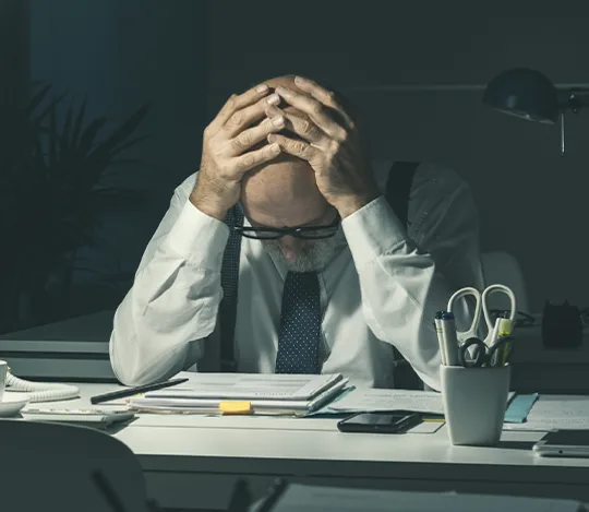 A person at a desk showing signs of stress and poor sleep