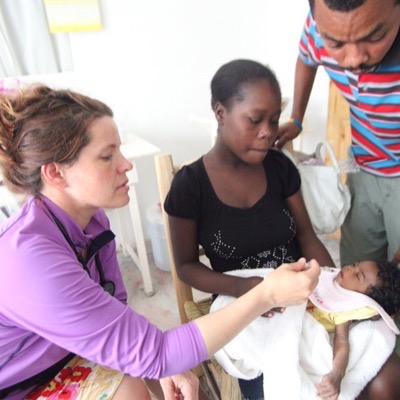 A clinician examining an infant held by its mother during a medical mission